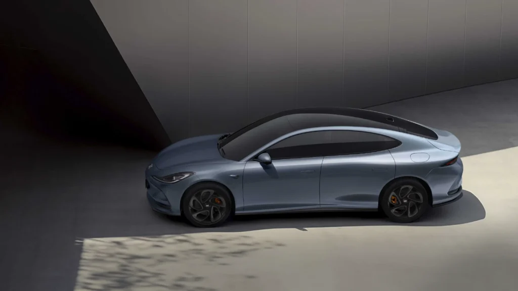 Sølvfarget elbil parkert ved moderne bygning.