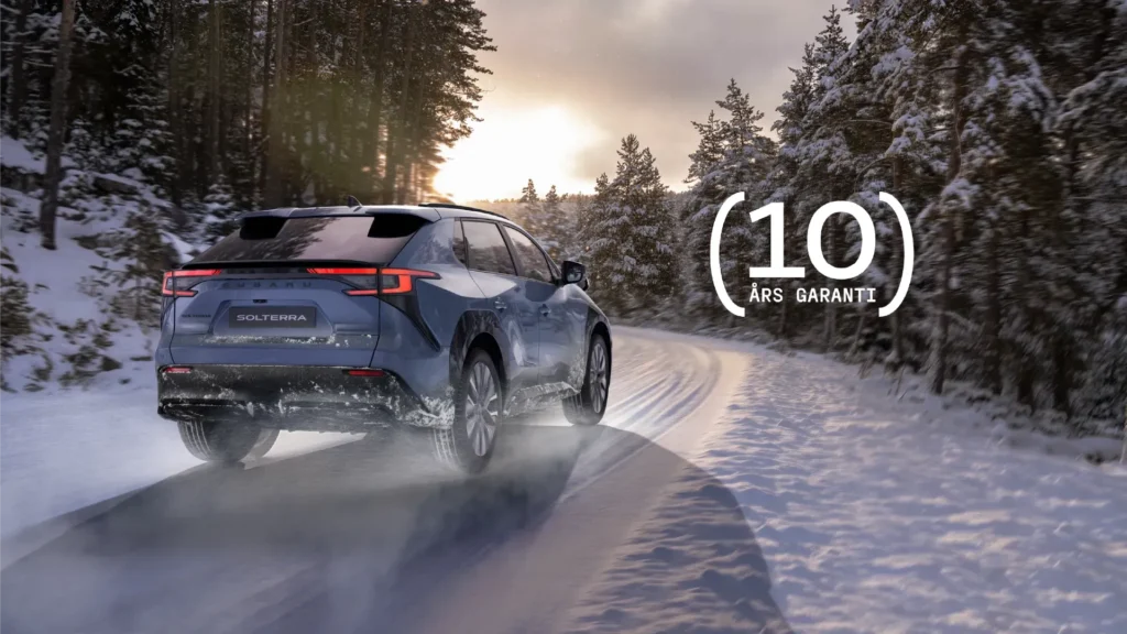 Blå Subaru SUV på snødekt vei, tekst: "10 års garanti".