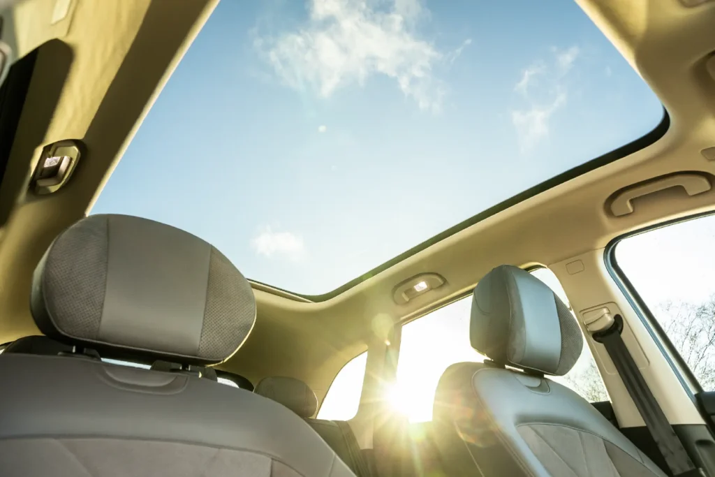 Sol og blå himmel gjennom panoramatak i bil.